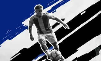 A Black soccer player in a striped jersey dribbles a ball against a graphic background of blue, black, and white stripes.