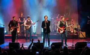 A band performs on stage with red and blue lighting.