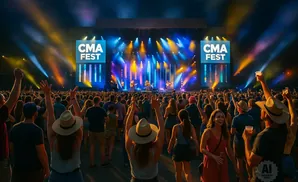 Crowd at a CMA Fest concert with a band performing on stage and bright lights.