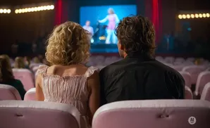 Couple watching a performance on stage at a venue with pink seats.