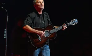 Man playing acoustic guitar on stage.