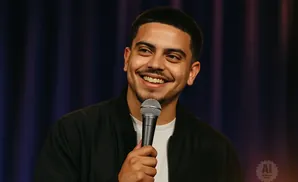 A man with short dark hair, a mustache, and a goatee smiles into a microphone.