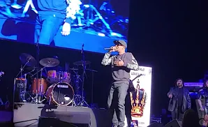 Rapper T.I. performs on stage with a drum set and backup singers.
