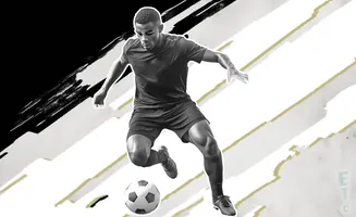 A black and white image of a soccer player in mid-air, dribbling a soccer ball.