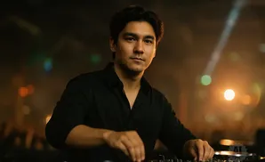 A man in a black shirt uses a DJ setup with lights in the background.