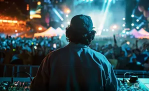 DJ performing at a lively outdoor concert with a cheering crowd.