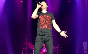 one vision of queen vocalist singing live on stage in front of purple lights