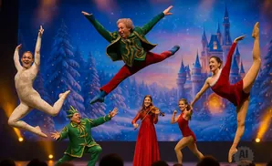 A troupe of dancers in festive attire perform on stage with a winter castle backdrop.