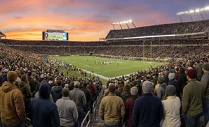 Crowd watching a football game at Camping World Stadium during sunset.