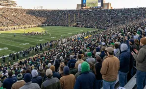 A football stadium full of fans watching a game on a sunny day.
