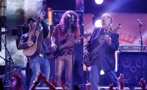 A band performs on stage, with three musicians playing guitars.