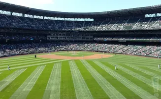 A baseball stadium with players on the field and spectators in the stands.