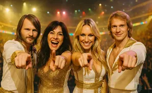 Four performers dressed in 1970s-style white and gold outfits point at the camera.