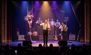A woman performs aerial acrobatics on a rope while a band plays on stage.