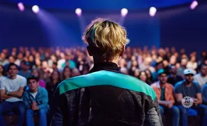 Person on stage faces a blurred audience under stage lights.