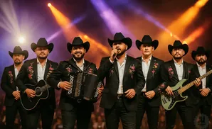 A band of men in cowboy hats and embroidered jackets perform on stage with colorful stage lights.
