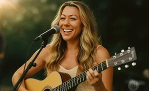 A woman smiles while playing an acoustic guitar and singing into a microphone outdoors.