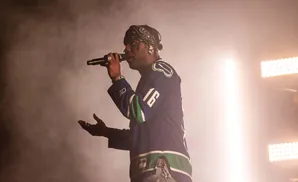 A rapper performs on stage wearing a blue hockey jersey and bandana.