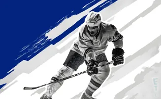 A hockey player in full gear skates forward with a stick.