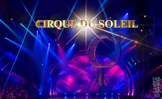 Cirque du Soleil stage with gold lettering, a large hoop, and dramatic blue and purple lighting.
