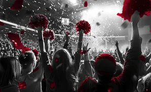 A crowd cheers with red pom-poms and red confetti raining down.