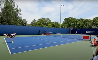 Tennis player serving on a blue court, with spectators and a 