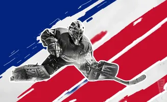 A hockey goalie in full gear makes a save against a backdrop of red and white stripes and a blue section.