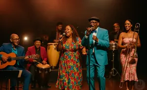 A band performs on stage with singers, a guitarist, and a trombonist.