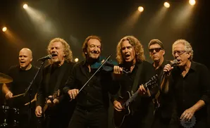 A band performs on stage, with members playing guitar, violin, and drums, all wearing black.