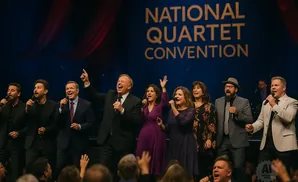 A group of singers performs on stage at the National Quartet Convention, with a banner behind them.