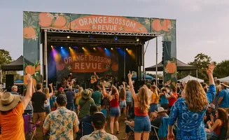 People enjoy an outdoor concert by the 