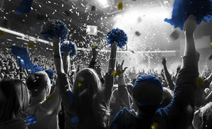 Crowd with blue and yellow pom-poms and confetti at a concert or sporting event.