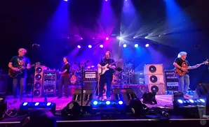 A band plays on a brightly lit stage with purple and blue lights.