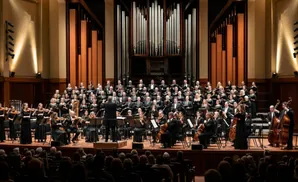 An orchestra and choir perform on a stage in front of a large organ.