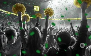 A crowd cheers, holding up golden pom-poms as green confetti rains down.