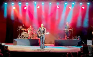 A band performs on stage with red and blue spotlights.