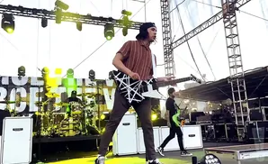 A band performs on a stage with yellow lighting.