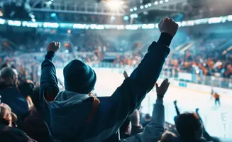 A fan cheers with fists in the air at a hockey game.