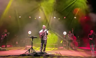 A band performs on stage with yellow and red lights.