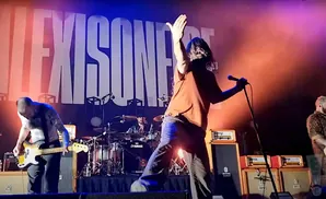 A band performs on stage with a large 