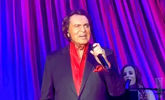 Singer Engelbert Humperdinck performs onstage with a woman singing in the background.