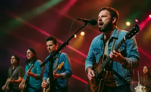A band performs on stage with colorful lights behind them. The lead singer is in the foreground playing guitar.