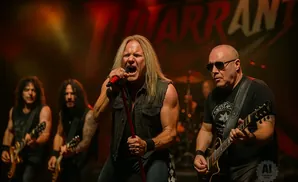 A rock band performs on stage with a singer in the foreground.