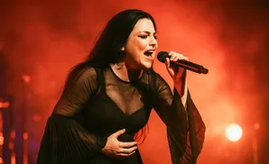 Singer Amy Lee of Evanescence performs on a stage with red lighting.