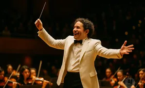 Conductor in a cream jacket and bow tie, animatedly leading an orchestra.