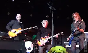 A band plays guitars on stage.