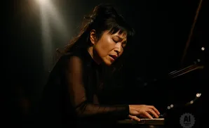 Woman playing a piano in dramatic lighting.