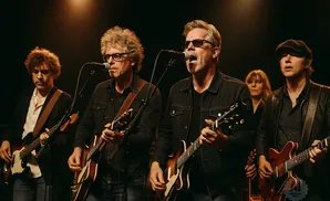 A band of musicians plays guitars on a stage.