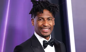 A man with dreadlocks in a tuxedo and bowtie smiles.