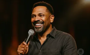 Mike Epps smiles and holds a microphone.